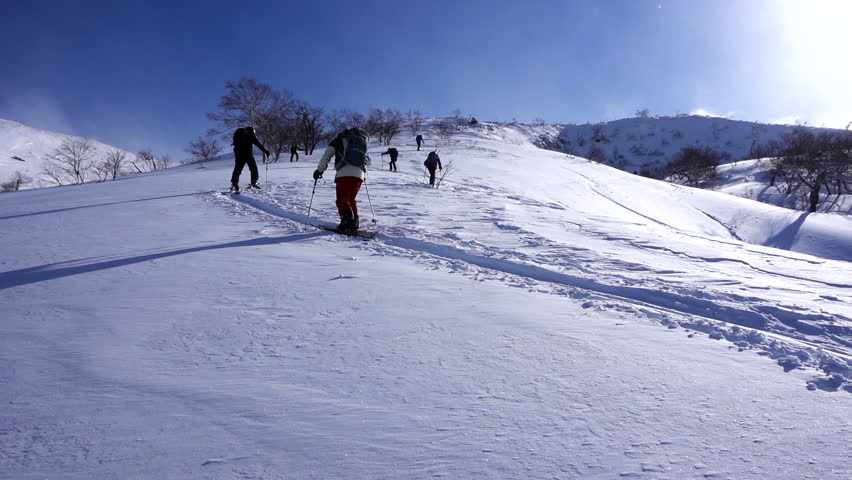 Hiking back up a skin track in the back country in slow-motion, blue bird day.
