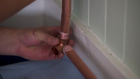 Plumber works on copper pipes, joins tubes. Prepare to solder. Close up.