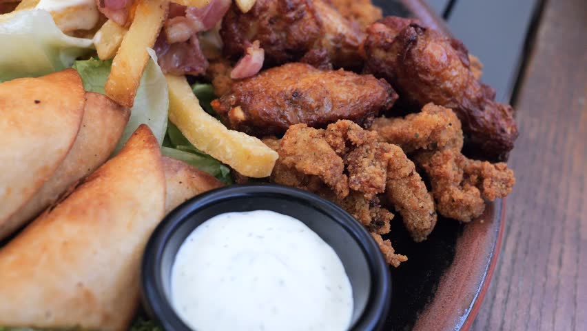 Plate with different types of hot snacks at the fresh air restaurant terrace