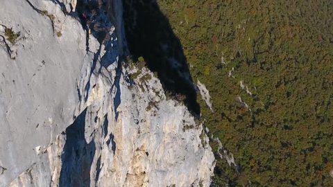 Man base jumping in slow motion from a cliff in choranche vercors massif France. Drone shot.