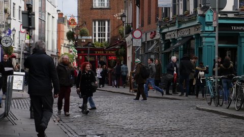 Dublin, Ireland - March 26th 2016: Temple Bar area of Dublin, Irish pubs with flowers outside. People walk by in street.