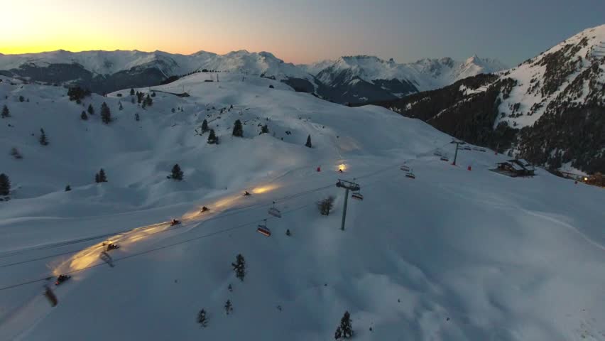 Snow mobiles during sunset in la plagne french alps by drone.