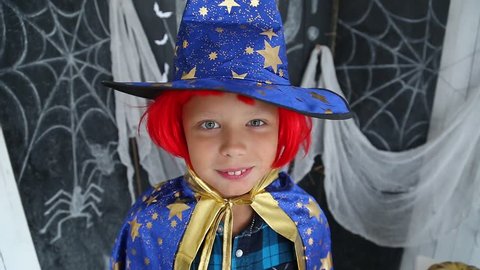 Closeup portrait of cute young boy wearing funny carnival costume and red wig ready for Halloween celebration. Funny kid screaming loudly trying to scare everyone.