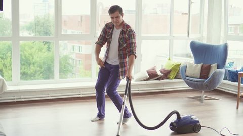 Funny man doing the cleaning vacuums and have fun dancing