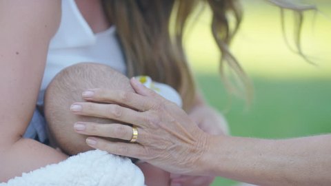 Grandparents hand stroking babies head as the child breastfeeds, in slow motion