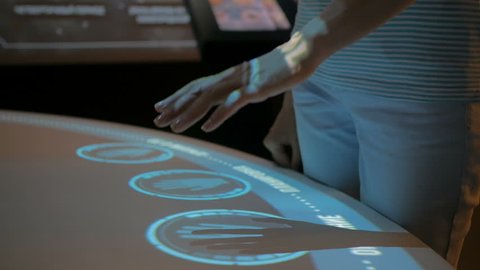 Woman using interactive touchscreen display with no touch control technology at modern history museum. Education and modern concept