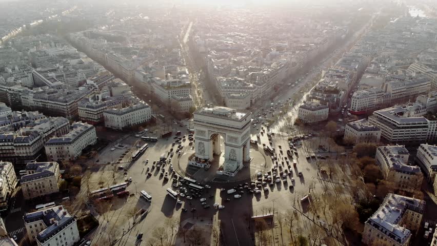 Aerial shot of the Arc de Triomphe and the traffic around it. Cars drive on the Champs Elysees. Paris in morning light. Royalty-Free Stock Footage #1013777141