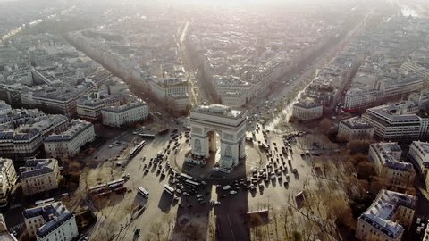 Aerial shot of the Arc de Triomphe and the traffic around it. Cars drive on the Champs Elysees. Paris in morning light.