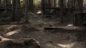 Cinematic slow motion clip of a mountain biker riding his bike down a technical trail, straight towards the camera.
