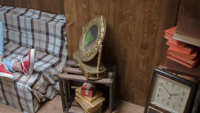 A young girl lying on the couch at home listening to music from the phone.