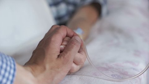 A man calming a woman in a hospital, holding her hand