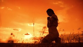 the girl prays. Girl folded her hands in prayer silhouette at sunset. slow motion video. Girl folded her hands in prayer pray to God. girl praying asks forgiveness for sins of repentance. believing