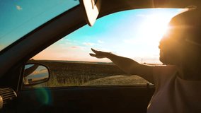Teen Waves Her Hand In The Wind In car slow motion video. Young happy young girl drives a car a holds her hand out from the window. Road trip, lifestyle travel and freedom concept