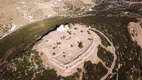 Aerial drone bird's eye view video of archaeological site of ancient citadel and chapel of Agios Andreas with view to Aegean, Sifnos island, Cyclades, Greece