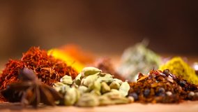 Spices. Various Indian Spices on wooden table. Spice and herbs rotated on wood background. Assortment of Seasonings, condiments. Cooking ingredients, flavor. Slow motion 4K UHD video