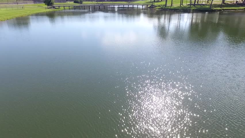 pan up crane shoot of a lake with a bridge of a park