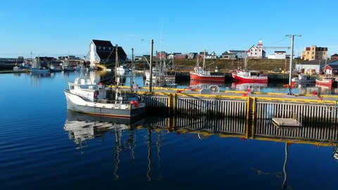 Beautiful drone footage of calm ocean water and colourful fishing boats in Bonavista, NL Canada