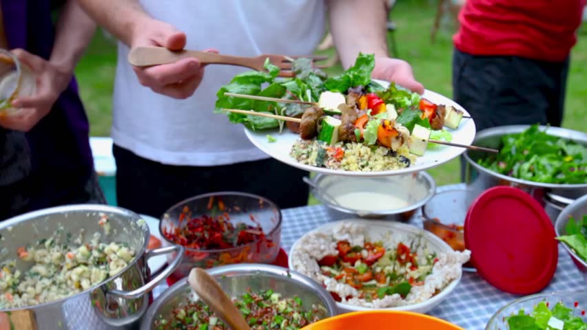 Close up on a man filling his plate with salad during an outdoor potluck (Package of 2 scenes, panning left, panning right) Royalty-Free Stock Footage #1013832896