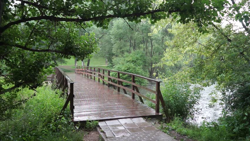Bicyclyst on the wet wooden bridge with rain