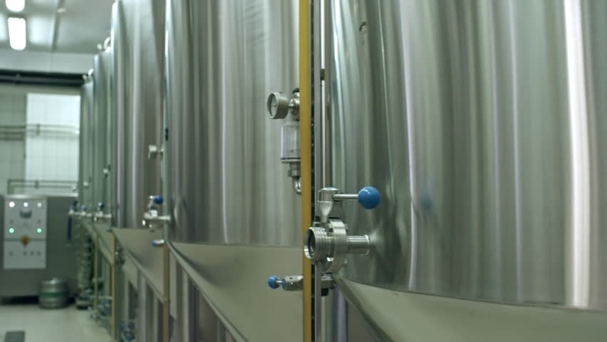 Close-up tracking shot of stainless steel tanks with beer in modern brewery, an Industrial Video by Pressmaster