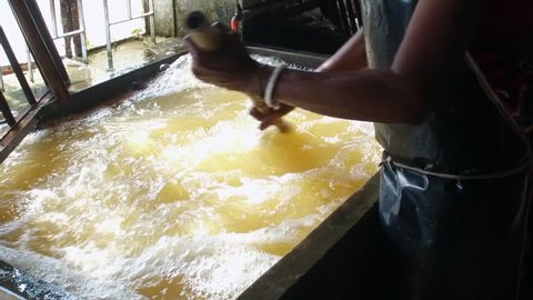 Bangladesh textile worker stirring vat of bubbling water