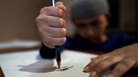 Frustrated ADHD afflicted young religious boy scribbling angrily on paper with pencil in school then ripping up sheet and crumpling into a ball