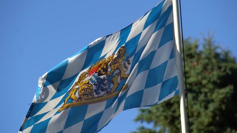 4K slow motion footage of bavarian flag waving in the wind with tree in the background