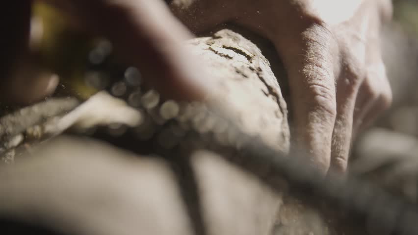 Elderly men is carving  wood in a cave. 