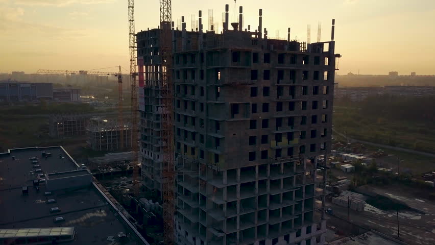 Drone flight under the building construction, the sun shines from behind the building, camera rises up, Russia, Chelyabinsk Royalty-Free Stock Footage #1013845181