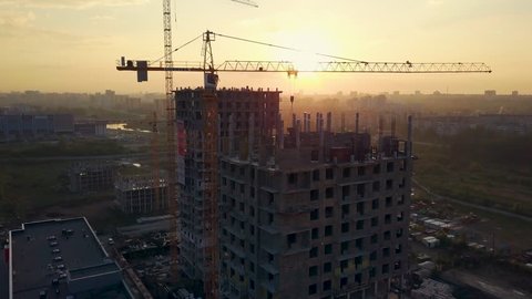 Drone flight under the building construction, the sun shines from behind the building, camera rises up, Russia, Chelyabinsk