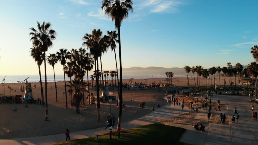 Venice Beach Drone in Los Angeles, CA with beautiful sunshine during summer next to The Pier on the Beachfront with Skaters skating in the park Royalty-Free Stock Footage #1013846627