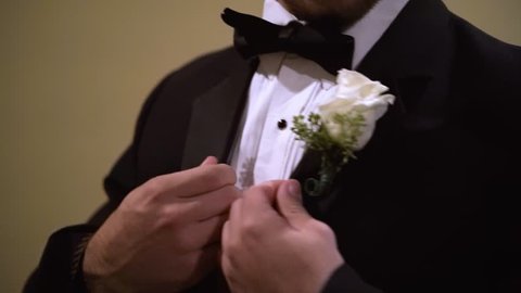 Woman places flower on a man's tux. He then adjusts the flower on his suit.