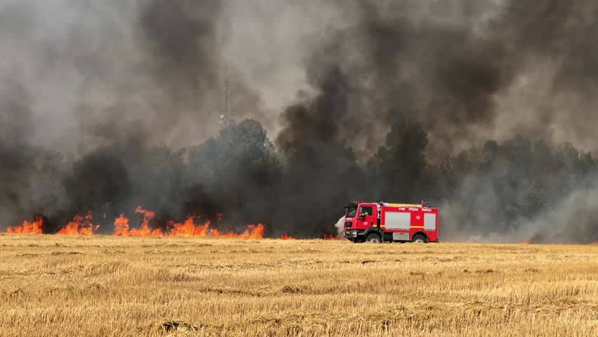 Fire engine turns off the fire in a wheat field. Fires in Israel that caused from burning kites and balloons that sent from the Gaza strip. 18.05.2018 in Nahal Oz fields, Israel.