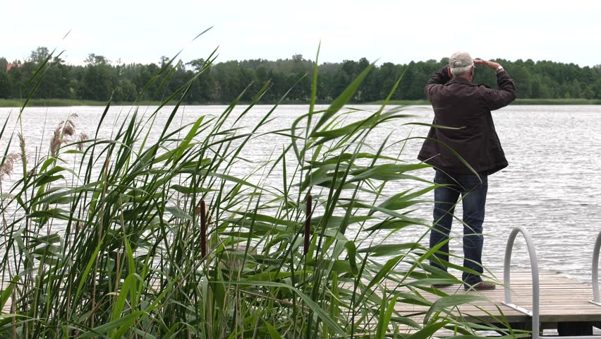 Man looks at the lake. It stands on the platform. 4K, UHD, 50p,Panning,Closeup, 						