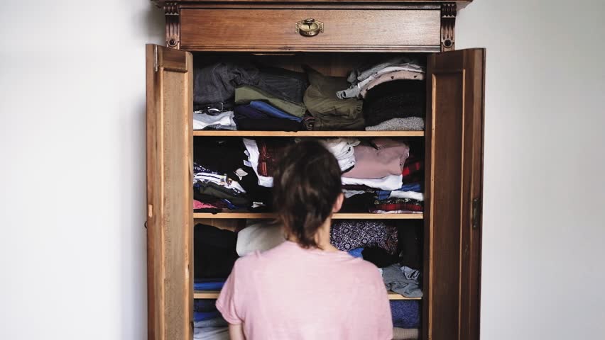 Angry young woman is throwing clothes from old retro vintage wooden wardrobe and after unsuccessful clothes search, view from back, slow motion 1920p HD Royalty-Free Stock Footage #1013848754