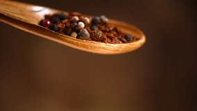 Spices falling from wooden spoon. Pepper, paprika, seasonings close-up.  Cooking concept, flavour. Various Indian Spices and herbs over brown background. Slow motion 4K UHD video