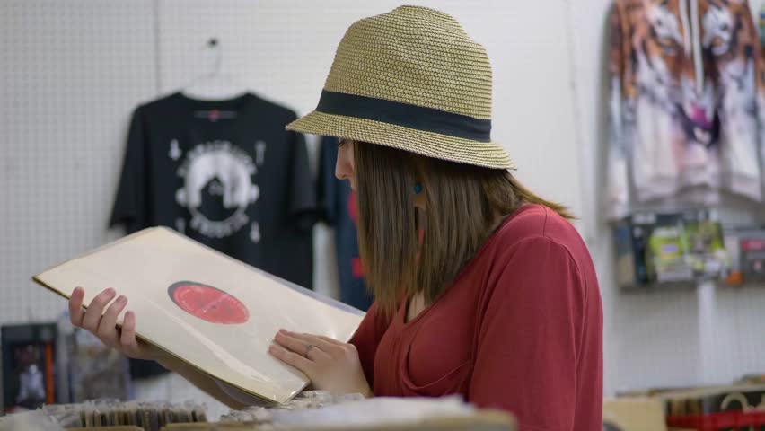 Young woman in hat looking through vinyl records Royalty-Free Stock Footage #1013861438