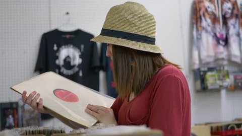 Young woman in hat looking through vinyl records