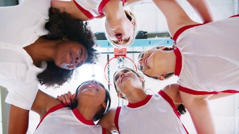 Low Angle View Of Female High School Basketball Players Having Team Talk With Coach
