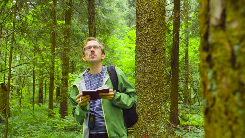 A scientist environmentalist exploring plants in a forest and writing data to a notebook Royalty-Free Stock Footage #1013869187