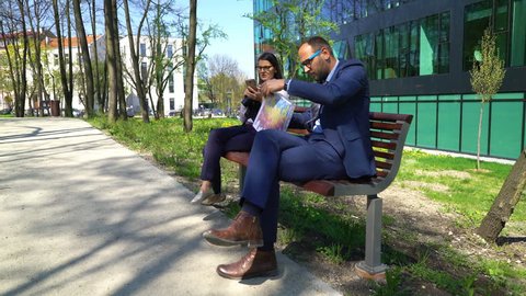 Young businessman and businesswoman with smartphone and documents in the city
