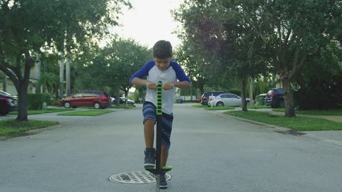Slow motion of kid jumping on a pogo stick around neighborhood