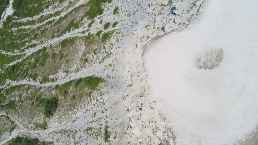 The camera flies over the viewing platform and flies backward from a sheer rock with swallows