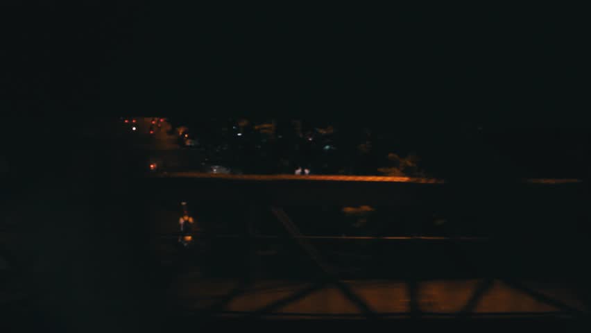 Streets of Vietnam, Hanoi, shot from inside a train. We see a bridge and a lots of traffic. Shot at night
