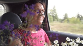 Laughing woman with bunch of flowers in the car