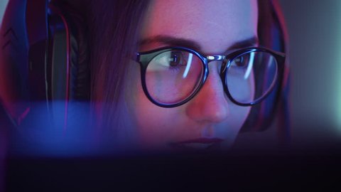 Beautiful Friendly Pro Gamer Girl Does Video Game Gameplaystream, Wearing Glasses. Attractive Geek Girl with Cool Neon Retro Colors in Background. Shot on RED EPIC-W 8K Helium Cinema Camera.