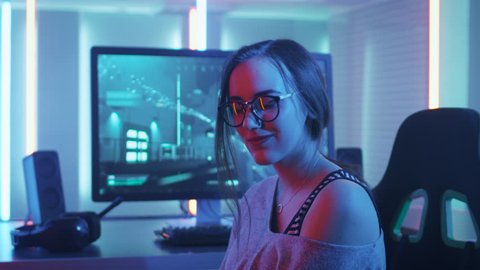 Portrait of the Beautiful Young Pro Gamer Girl Sitting at Her Personal Computer and Winning Online Video Game Tournament Looks into Camera. Shot on RED EPIC-W 8K Helium Cinema Camera.