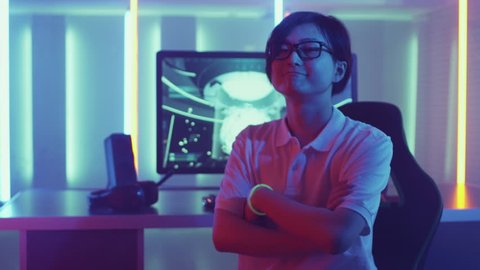 East Asian Pro Gamer Playing in Video Games Turns around and Smiles After winning Online Tournament. Stylish Neon Retro Arcade Room. Shot on RED EPIC-W 8K Helium Cinema Camera.