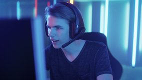 Young Pro Gamer Playing in Online Video Game, talks with Team Players through Microphone. Neon Colored Room. e-Sport Cyber Games Internet Championship. Shot on RED EPIC-W 8K Helium Cinema Camera.