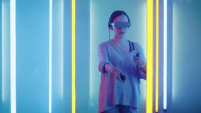 Beautiful Young Girl Wearing Virtual Reality Headset Draws Abstract Lines and Figures with Joysticks  Controllers. Creative Young Girl Does Concept Art with Augmented Reality.  Shot on RED EPIC-W 8K 